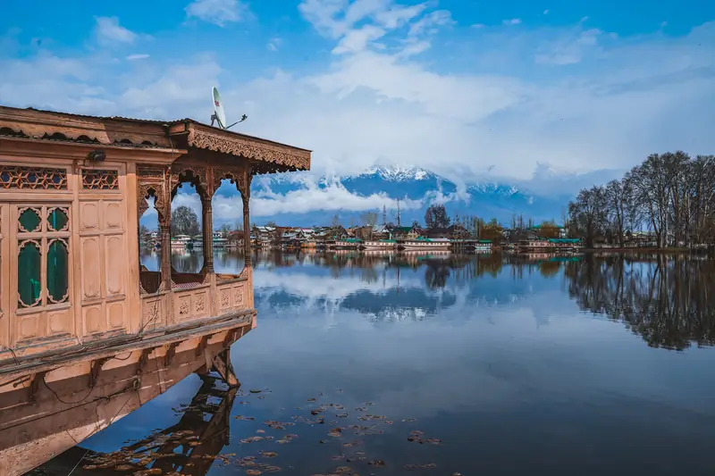 Houseboat moored on Dal Lake with snow-capped peaks behind, Srinagar
